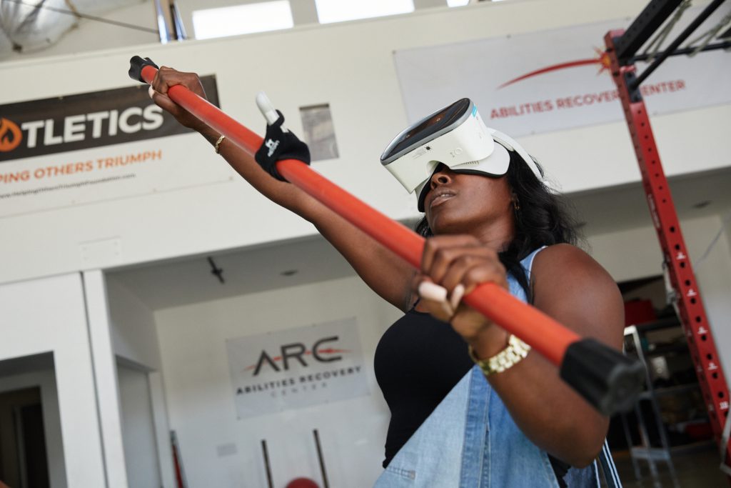 A MIERON user reaching overhead with a resistance bar during VR therapy